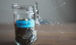 coins in a jar with blue tape on which is written "donate"