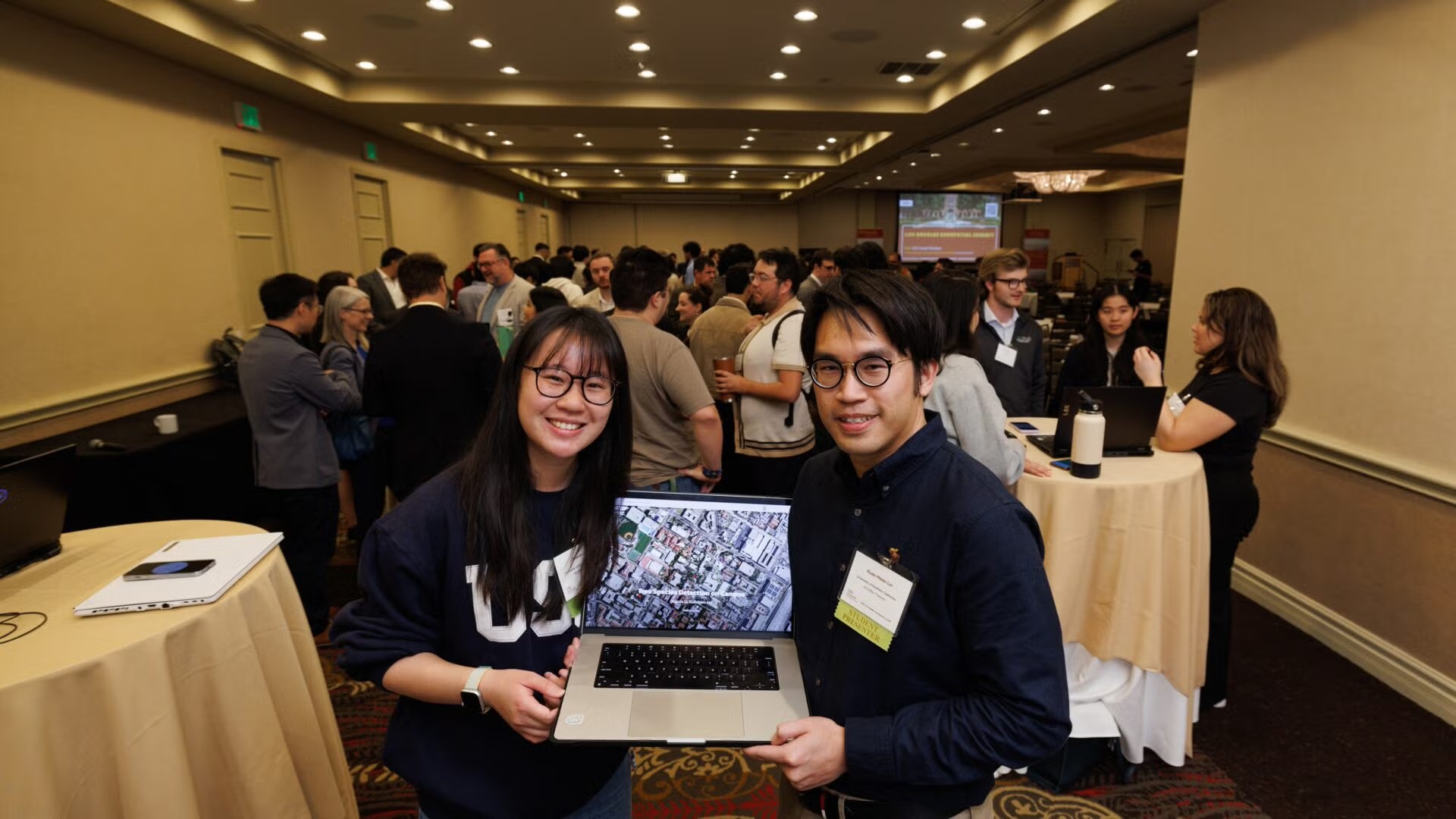 a female on the left and a male on the right holding a laptop open between the two of the. 
