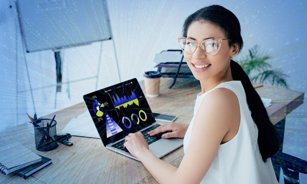 A woman, working at a laptop computer, turns to smile