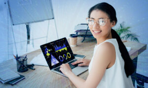 A woman, working at a laptop computer, turns to smile