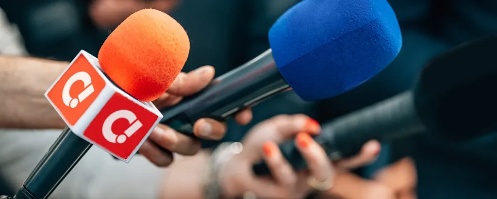 Reporters holding microphones at a press conference